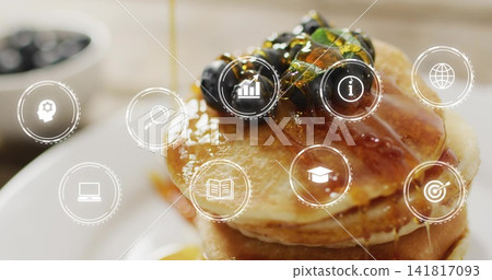 Pouring syrup over stack of pancakes on counter, with blueberries, pistachios and UI icons 141817093