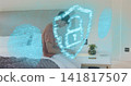 Using device, man in rust T-shirt leaning on bed in modern bedroom, with security hologram 141817507