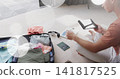 Packing man in rust tee and light pants at home, organizing passport wallet suitcase, copy space 141817525
