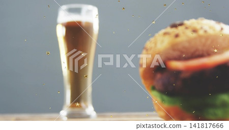 Displaying seeded hamburger at right on wooden tabletop, with tall glass and gold stars, copy space Displaying seeded hamburger at right on wooden tabletop, with tall glass and gold stars, copy space 141817666