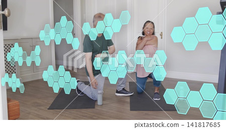 Kneeling couple in workout clothes stretching on mats at home, with water bottle and AR hexagons Kneeling couple in workout clothes stretching on mats at home, with water bottle and AR hexagons 141817685