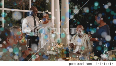 Holding wine glasses, six adults in semiformal attire chatting around porch table, with candles 141817717