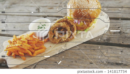 Displaying sesame-seed cheeseburger, onion rings, sweet-potato fries and ramekin on weathered board Displaying sesame-seed cheeseburger, onion rings, sweet-potato fries and ramekin on weathered board 141817734