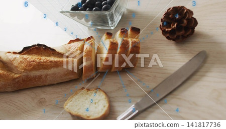 Displaying sliced baguette on wood board with slice and crumbs blueberries knife pinecone overlay Displaying sliced baguette on wood board with slice and crumbs blueberries knife pinecone overlay 141817736