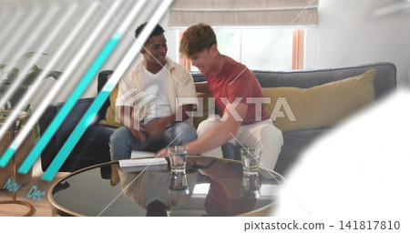 Chatting two men in casual clothes leaning, reaching papers on glass coffee table in living room Chatting two men in casual clothes leaning, reaching papers on glass coffee table in living room 141817810
