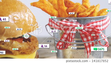 Displaying cheeseburger and pail of fries with gingham ribbon on wooden table with social overlays Displaying cheeseburger and pail of fries with gingham ribbon on wooden table with social overlays 141817852