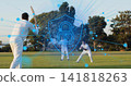 Batting batter holding wooden bat with team in whites at local field, showing blue padlock overlay 141818263