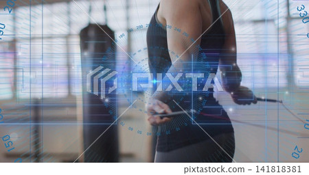 Holding jump rope athlete wearing tank standing in studio with windows HUD punching bag, copy space Holding jump rope athlete wearing tank standing in studio with windows HUD punching bag, copy space 141818381