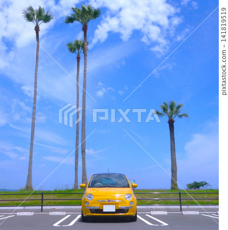 一輛黃色義大利轎車停在棕櫚樹環繞的停車場。 一輛黃色義大利轎車停在棕櫚樹環繞的停車場。 141819519