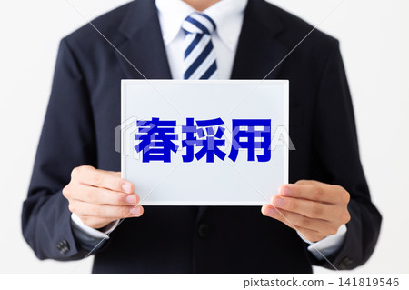 A young businessman in a business suit holding a whiteboard advertising spring recruitment. A young businessman in a business suit holding a whiteboard advertising spring recruitment. 141819546