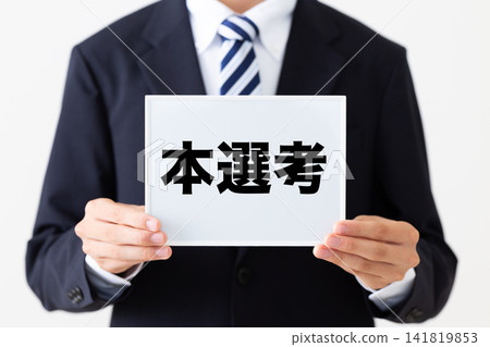 一位身穿西裝的年輕商人手持白板,準備進行最終篩選。 一位身穿西裝的年輕商人手持白板,準備進行最終篩選。 141819853