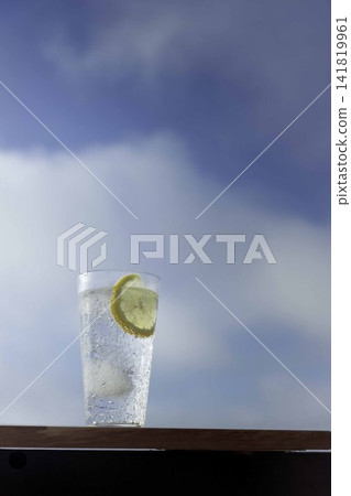 Lemon-flavored sparkling water against a blue sky – a refreshing summer drink. Lemon-flavored sparkling water against a blue sky – a refreshing summer drink. 141819961