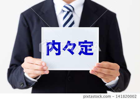 A young businessman in a business suit holding a whiteboard with an informal job offer. A young businessman in a business suit holding a whiteboard with an informal job offer. 141820002