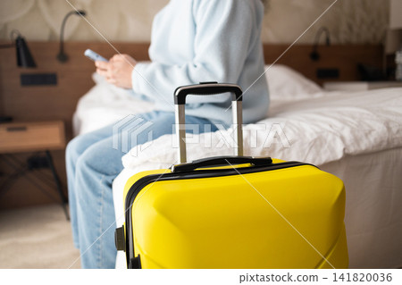 Man with yellow suitcase sitting on bed in hotel room Man with yellow suitcase sitting on bed in hotel room 141820036