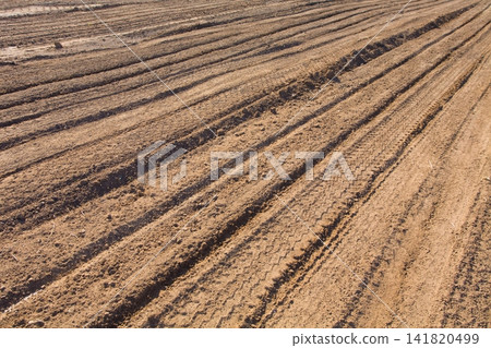 Texture brown yellow clay earth with traces of cars, trucks, tractors. Road with tire tracks. Texture brown yellow clay earth with traces of cars, trucks, tractors. Road with tire tracks. 141820499