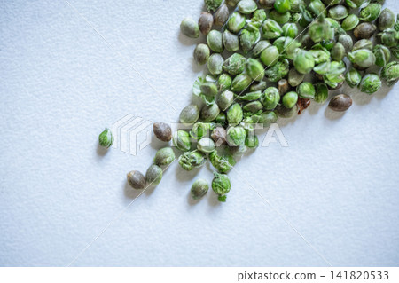 Green hemp seeds scattered on white textured background in natural light top view macro Green hemp seeds scattered on white textured background in natural light top view macro 141820533