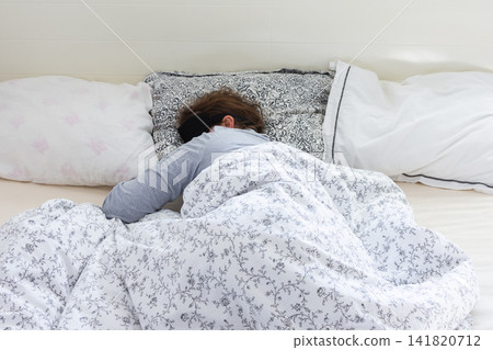 A 50-year-old woman is comfortably sleeping in her bed with a sleep mask on. She is wrapped in a soft blanket, resting peacefully in a serene bedroom setting A 50-year-old woman is comfortably sleeping in her bed with a sleep mask on. She is wrapped in a soft blanket, resting peacefully in a serene bedroom setting 141820712