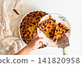 A woman slices a homemade cherry and currant pie, this pie combines cherry and currant flavors with sourdough for a delicious treat 141820958