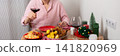A man is cooking dinner for Christmas by baking chicken with potatoes in his kitchen. He is sitting at the table, ready to enjoy the meal with a glass of wine, banner 141820969