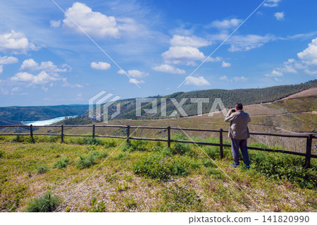 The resting place with a beautiful view of the mountain near the Zezere river. A man tourist takes a photo. Ferreira do Zezere, Portugal The resting place with a beautiful view of the mountain near the Zezere river. A man tourist takes a photo. Ferreira do Zezere, Portugal 141820990