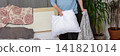 A 53-year-old man replaces the bed linen in his bedroom. He gathers clean sheets and works on making the bed comfortable for sleeping, banner 141821014