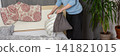 A 53-year-old man replaces the bed linen in his bedroom. He gathers clean sheets and works on making the bed comfortable for sleeping, banner 141821015