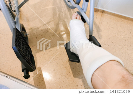 A leg in a cast resting on the wheelchair footrest. 141821059