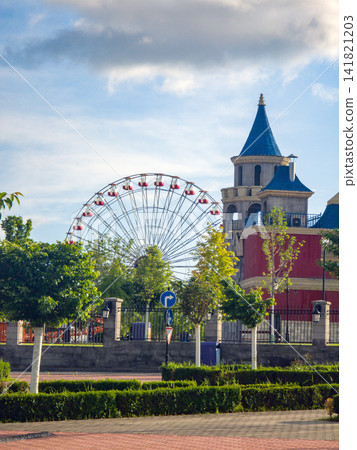 Ferris wheel and ornate tower with blue roofs 141821203