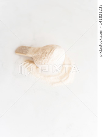 Scoop of white protein powder for sports nutrition on a light background. Scoop of white protein powder for sports nutrition on a light background. 141821235
