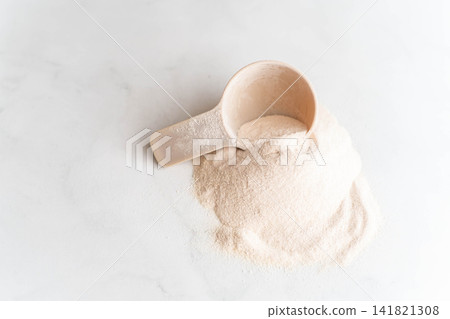 Scoop of white protein powder for sports nutrition on a light background Scoop of white protein powder for sports nutrition on a light background 141821308
