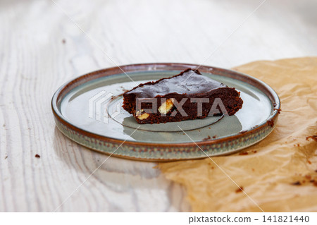 Side view of a triangular slice of homemade chocolate almond brownie served on a ceramic plate. Selective focus Side view of a triangular slice of homemade chocolate almond brownie served on a ceramic plate. Selective focus 141821440