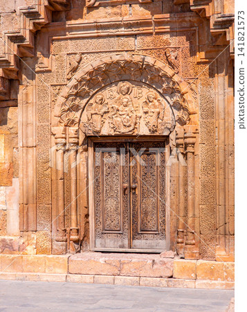 Close-up of ornate stone entrance with carved arch and metal doors Close-up of ornate stone entrance with carved arch and metal doors 141821573