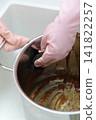A housewife's hands as she tries to remove curry stains from a pot. 141822257