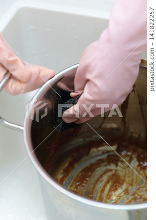 A housewife's hands as she tries to remove curry stains from a pot. A housewife's hands as she tries to remove curry stains from a pot. 141822257