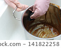 A housewife's hands as she tries to remove curry stains from a pot. 141822258