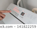 A woman's finger pressing the washing machine switch 141822259
