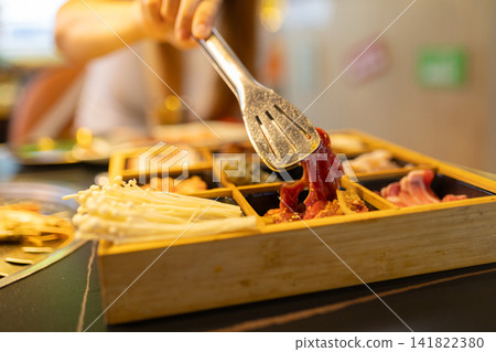 Hand picking raw meat from set for korean barbecue Hand picking raw meat from set for korean barbecue 141822380