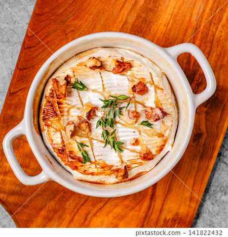 Baked cheese with honey and walnuts on a wooden board Baked cheese with honey and walnuts on a wooden board 141822432