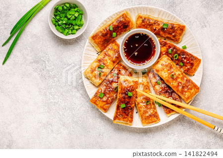 Dumplings are arranged on a plate with a small bowl of dipping sauce Dumplings are arranged on a plate with a small bowl of dipping sauce 141822494
