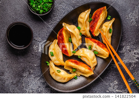 Dumplings are served on a black plate with green onion Dumplings are served on a black plate with green onion 141822504