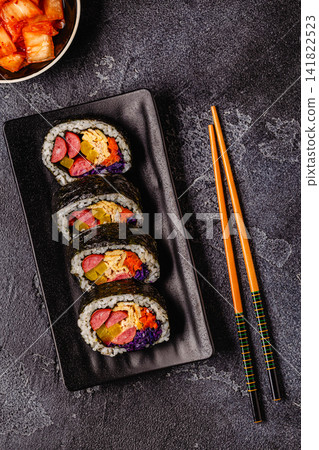 A black plate filled with kimbap (or gimbap) that have colorful fillings. A black plate filled with kimbap (or gimbap) that have colorful fillings. 141822523