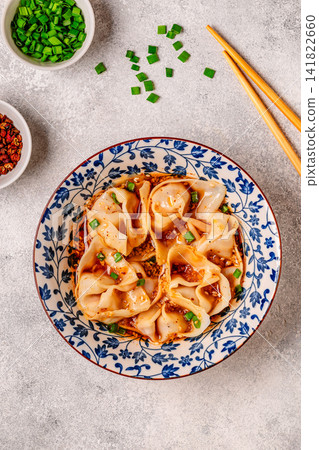 Wontons are placed in a bowl with spicy sauce. Wontons are placed in a bowl with spicy sauce. 141822660