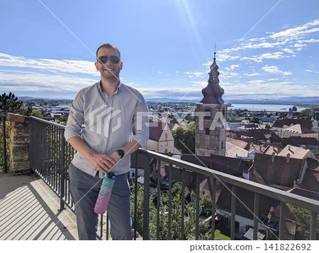 Man traveler looking at beautiful panorama of old town from Ptuj castle walls in Slovenia Man traveler looking at beautiful panorama of old town from Ptuj castle walls in Slovenia 141822692