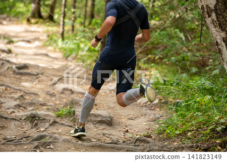 Dynamic running athlete along forest trail Dynamic running athlete along forest trail 141823149