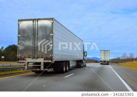 Trucks drive side by side on highway with mountains in South Carolina under cloudy sky. Trucks drive side by side on highway with mountains in South Carolina under cloudy sky. 141823301