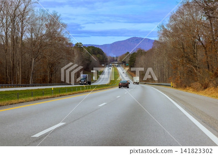 Highway stretches ahead with cars driving toward distant mountains into North Carolina Highway stretches ahead with cars driving toward distant mountains into North Carolina 141823302