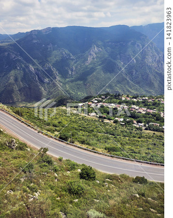 Road curves gracefully through verdant valley with mountain backdrop Road curves gracefully through verdant valley with mountain backdrop 141823963