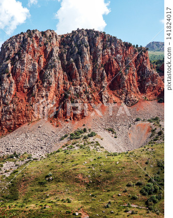 Rugged, red-brown cliff face dominates the landscape Rugged, red-brown cliff face dominates the landscape 141824017