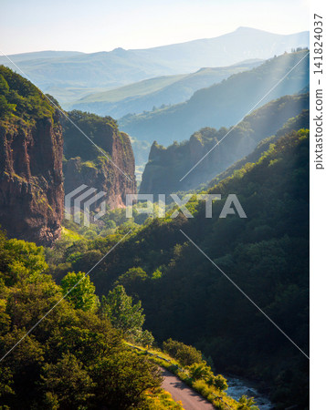 Mountain valley scene with sunlit cliffs, river, and winding path Mountain valley scene with sunlit cliffs, river, and winding path 141824037
