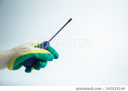 Close-up of a gloved hand holding a screwdriver on a white background. The concept of repair, twisting, handyman, construction, tools. High quality photo Close-up of a gloved hand holding a screwdriver on a white background. The concept of repair, twisting, handyman, construction, tools. High quality photo 141824144